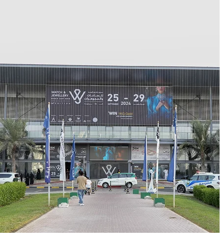A large billboard advertising watches and jewelry, with a parked car in front of it.