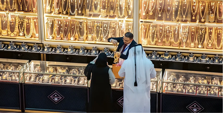 A man and woman examine gold jewelry displayed in a store, showcasing their interest in the elegant pieces.