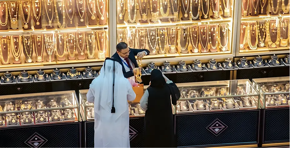 A man and woman examine gold jewelry displayed in a store, showcasing their interest in the elegant pieces.